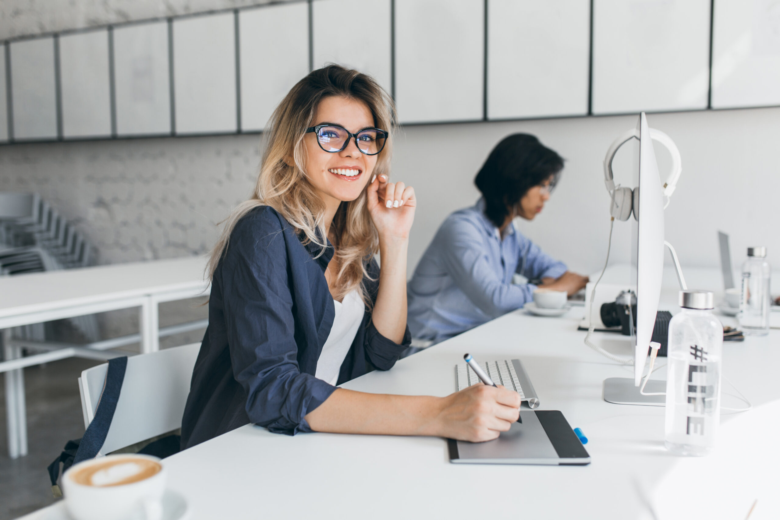 Beautiful female office worker carrying out administrative work for company. Indoor portrait of cute blonde student doing homework with asian universuty friend..